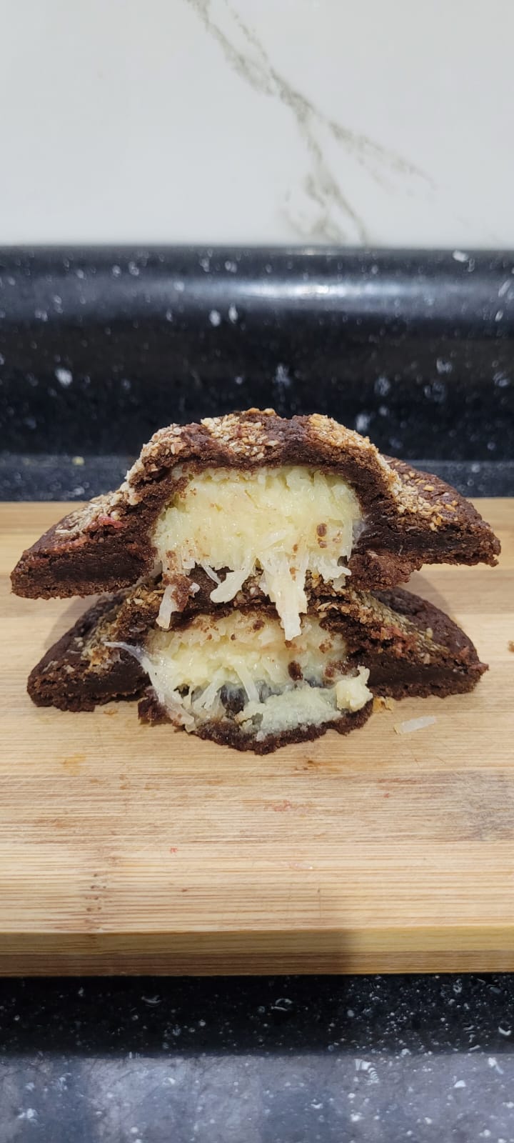 Cookie Prestígio partido ao meio, com recheio cremoso de coco
